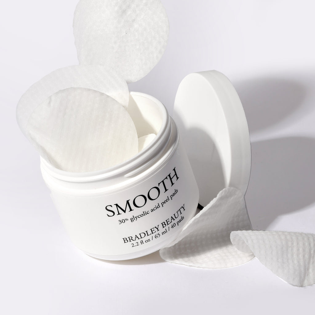 A open tub of SMOOTH 30% Glycolic Acid Peel Pads with peel pads flying out of it.