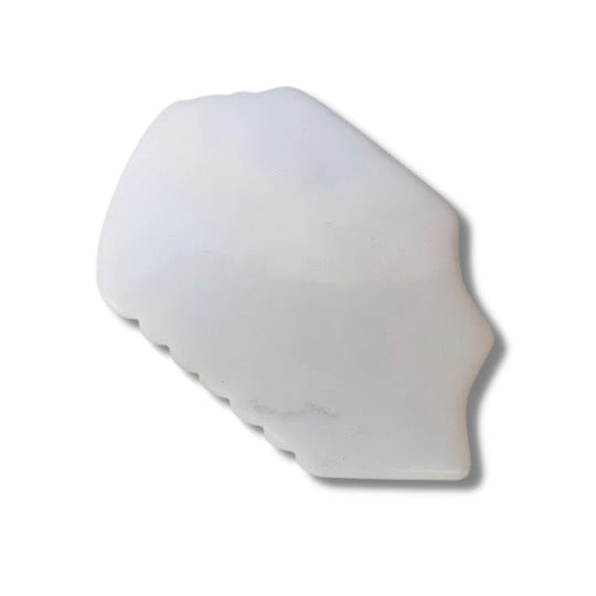 Milky quartz stone shaped into an ergonomic facial and body massaging tool, featuring multiple curved and scalloped edges for massaging different parts of the face and body.